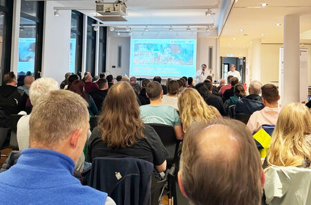Menschen in Sitzreihen mit Blick auf eine Leinwand